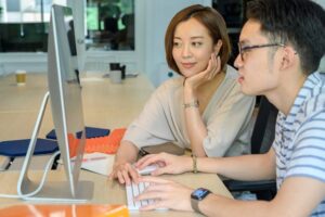 Man and Woman Typing on a White Keyboard 